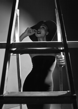 Γυναίκα με μαύρο φόρεμα σε πόζα πάνω στην σκάλα