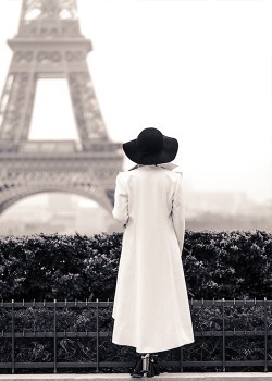 Γυναίκα με άσπρο παλτό που παρατηρεί τον πύργο του Άιφελ