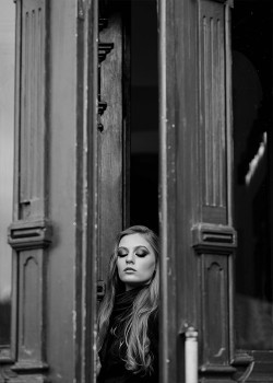 Κοπέλα στέκεται μπροστά σε μια ξύλινη πόρτα