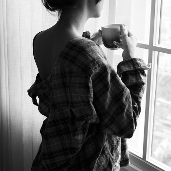 Κοπέλα που πίνει καφέ στο παράθυρό της
